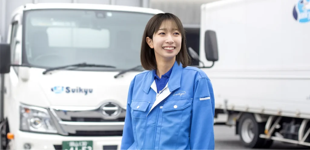 トラックの前で笑顔の女性社員