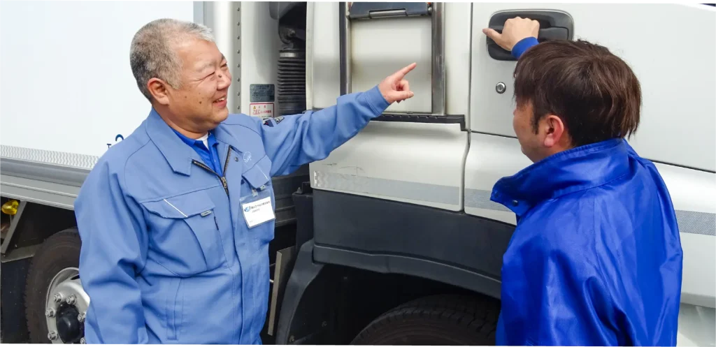 トラックの前で先輩社員と話をする男性社員